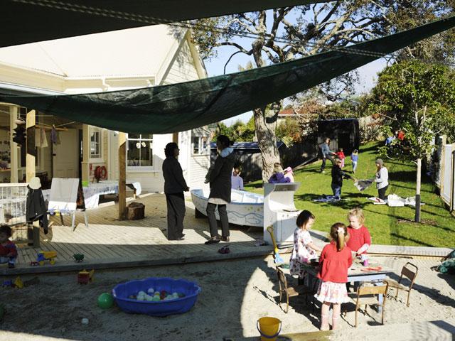 Children playing in a sand area under a shade sail