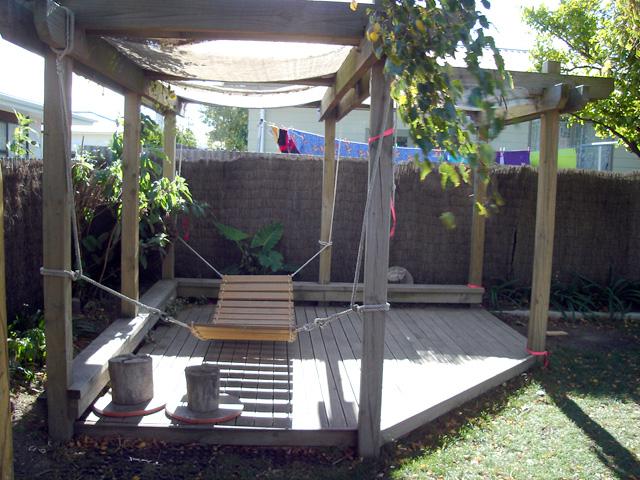 Wooden swing bridge under a shaded wooden gazebo