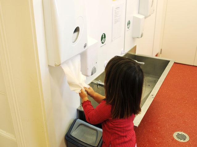 Girl using hand towel dispenser