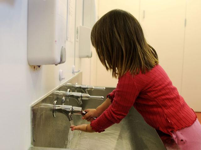 Girl washing her hands in trough sink